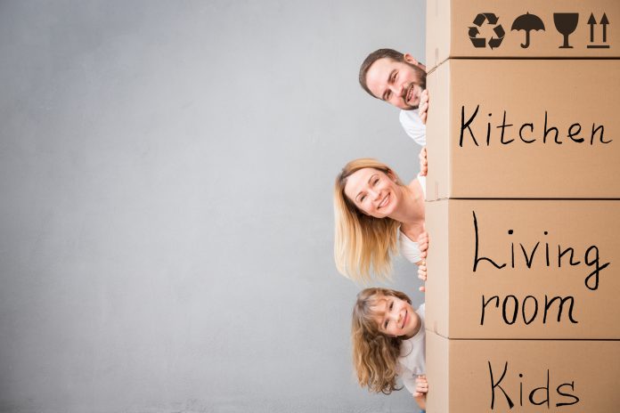 Family New Home Moving Day House Concept family-next-to-moving-boxes